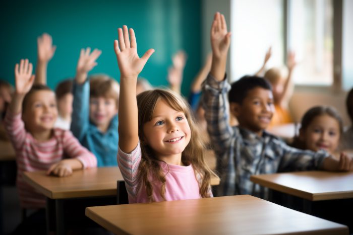 Children raise their hands to answer in the classroom
